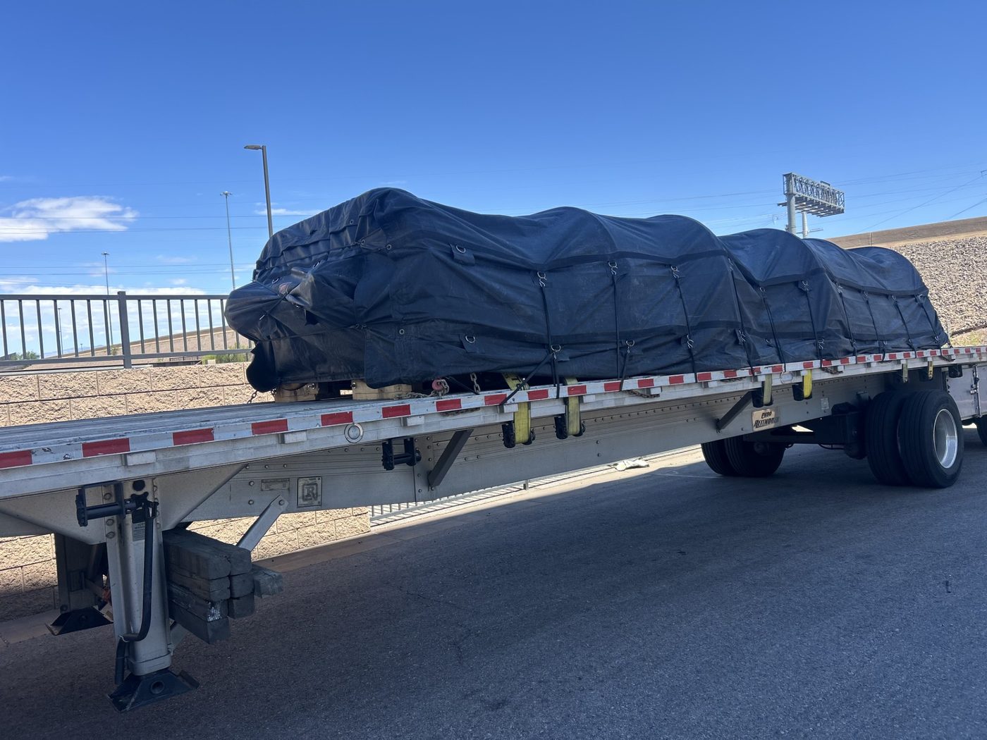 Tarped load strapped down on a flatbed trailer